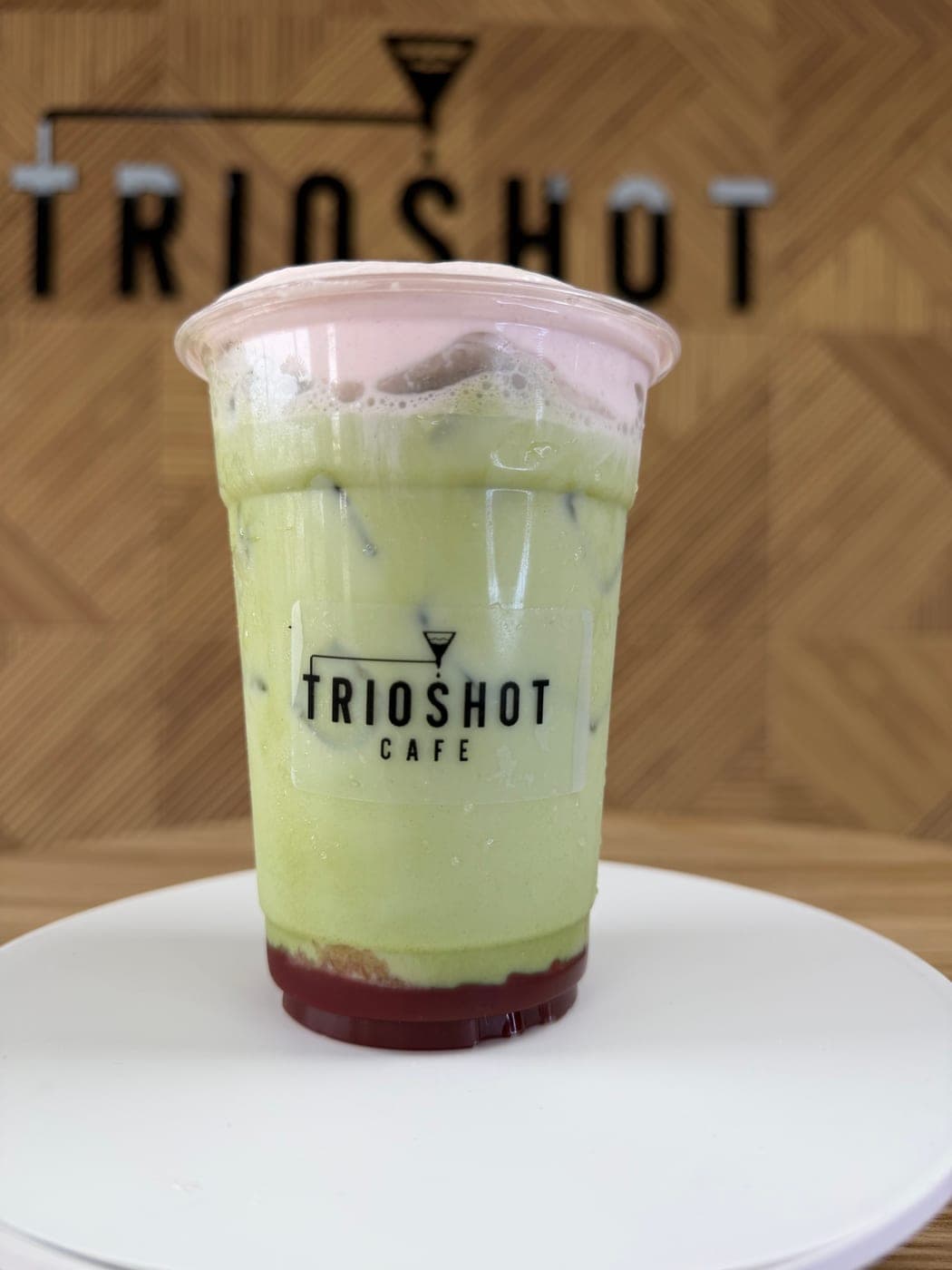 Iced strawberry matcha latte in a TRIOSHOT CAFE cup