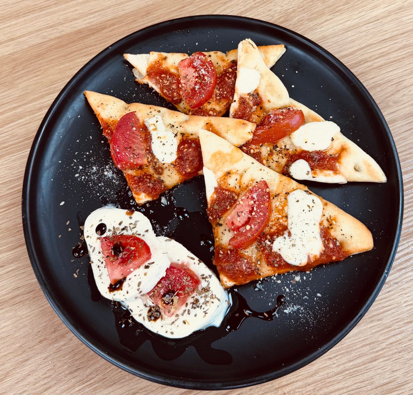Cheese pizza bites on a black TRIOSHOT CAFE plate
