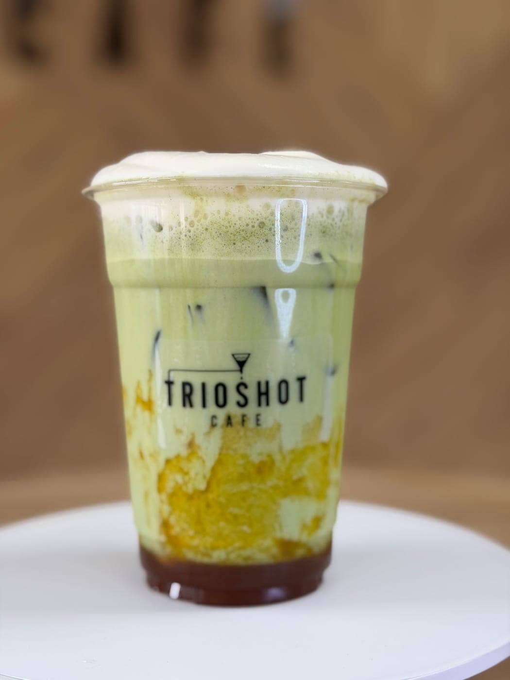 Iced mango matcha latte in a clear TRIOSHOT CAFE cup