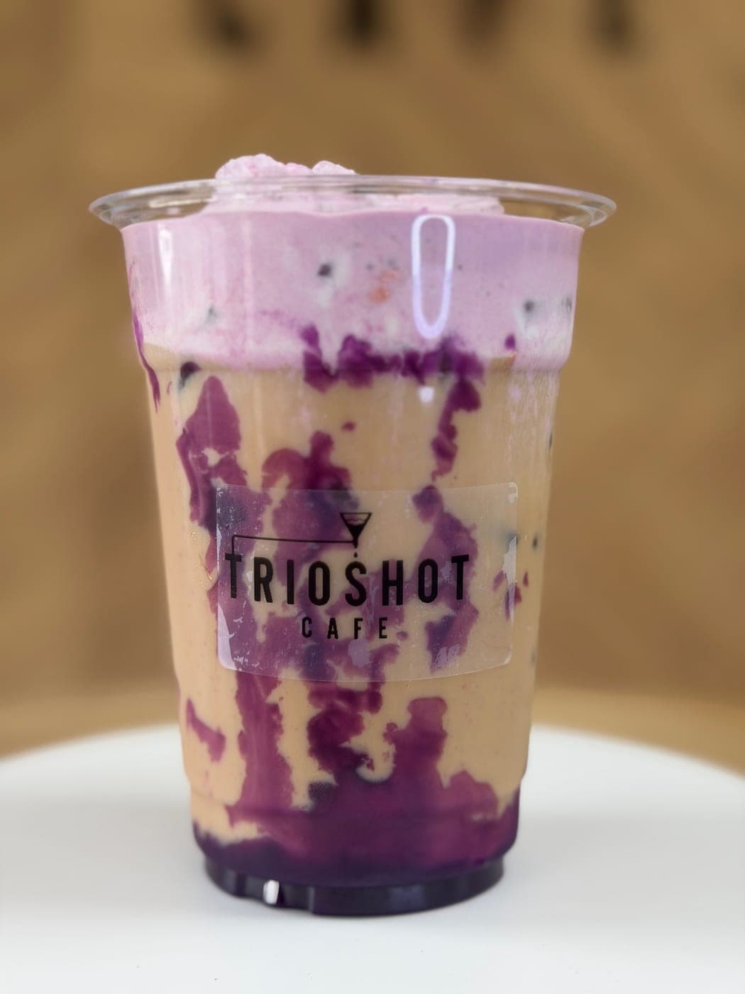 Purple ube berry iced drink in a TRIOSHOT CAFE cup