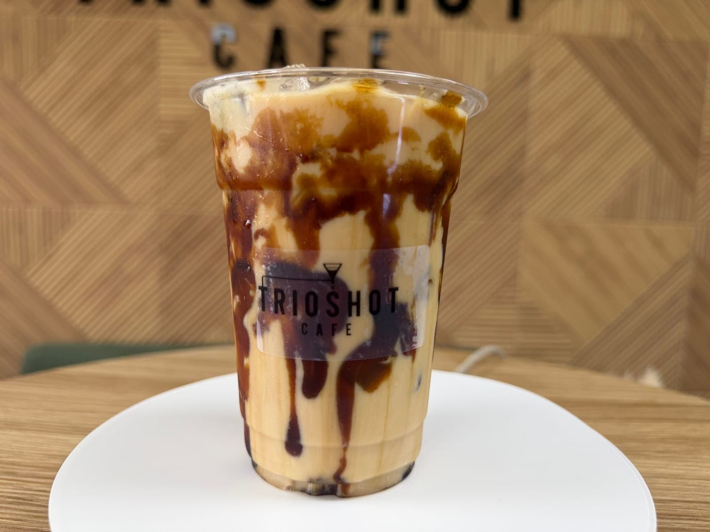 Chocolate caramel iced latte in a clear TRIOSHOT CAFE cup
